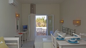 Una habitación con cama, televisión, una mesa de comedor y platos azules, y vistas al exterior.