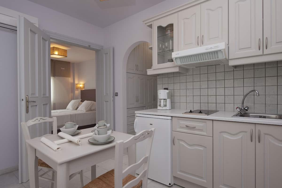 A modern kitchen with white cabinetry, a coffee maker, and a dining area with a table set for two.