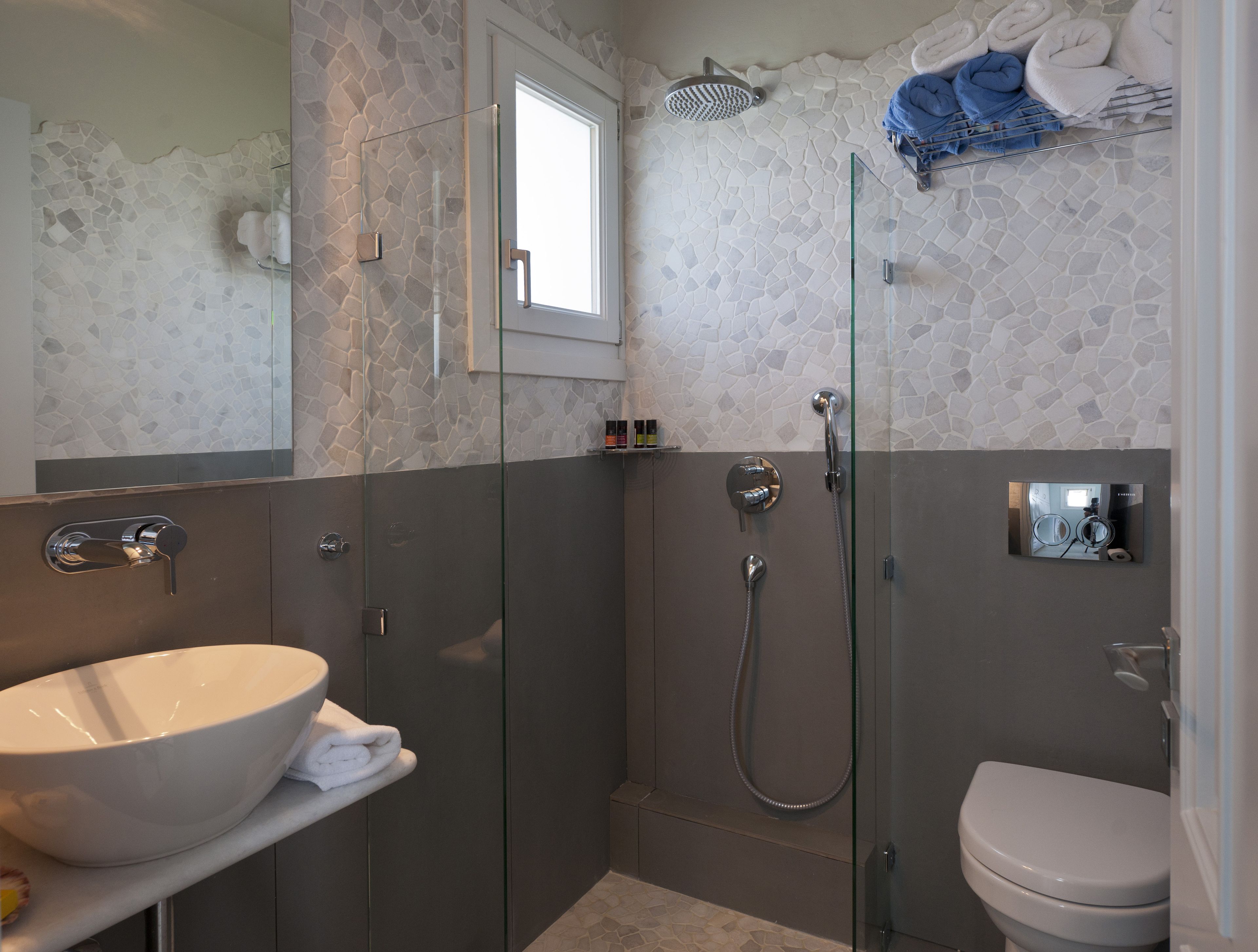 Un baño moderno con ducha de vidrio, un lavabo blanco y un inodoro.