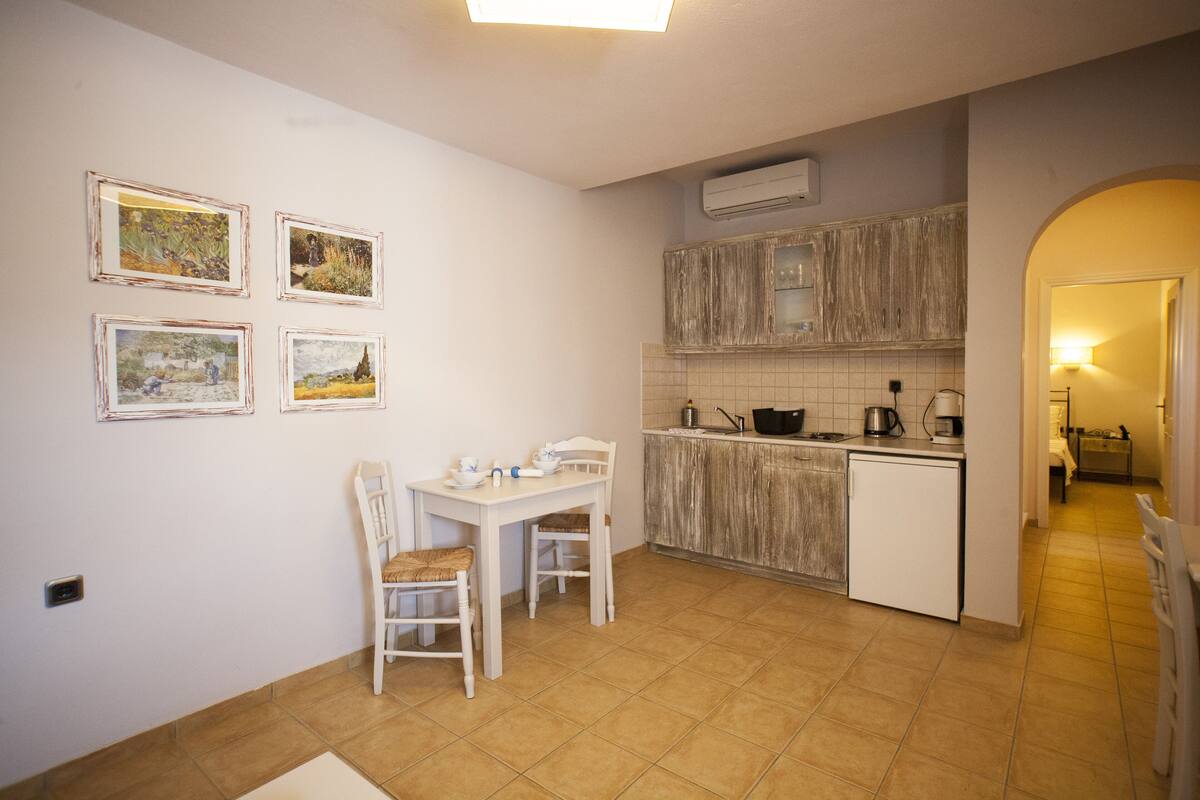 A compact kitchen with a dining area, featuring a small table and chairs, a tiled backsplash, and a built-in oven.