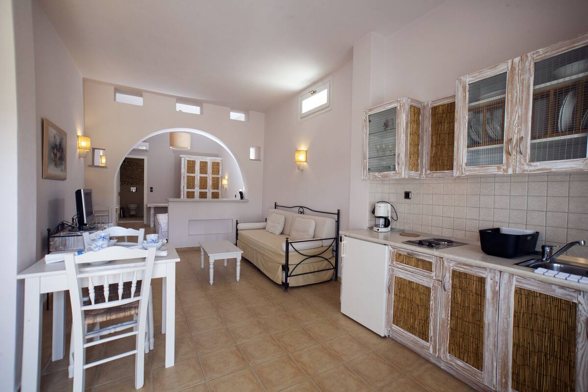 A compact kitchen with a dining area, a bed, and a small table.