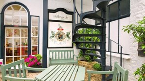 Un cortile con una scala a chiocciola, sedute verdi e un negozio chiamato 'Marlborough'.
