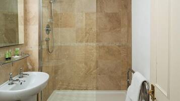 A bathroom with a glass-enclosed shower, a white sink, and a towel rack.