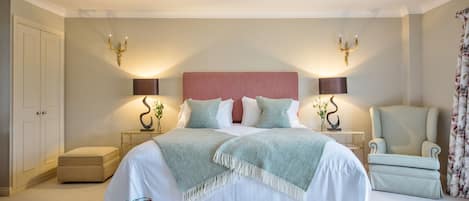 A neatly arranged bedroom with a large bed, two bedside tables, a chair, and a wardrobe.