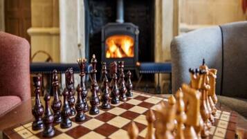 Un tablero de ajedrez dispuesto en una habitación con una chimenea al fondo.