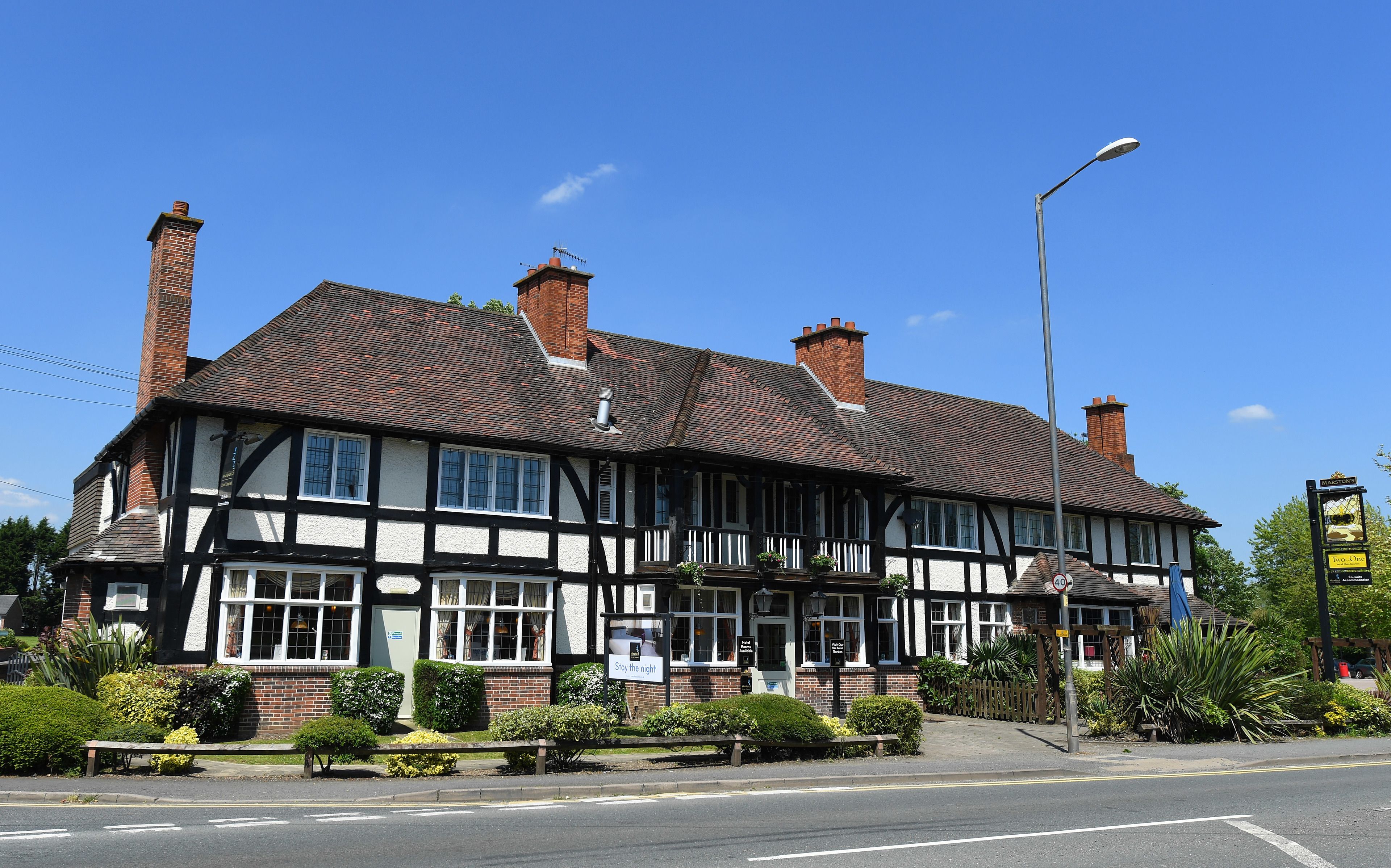 Un edificio de estilo Tudor tradicional con fachada blanco y negra, múltiples chimeneas y un letrero que dice 'Pase la noche'.