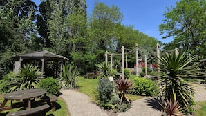 A garden with a wooden gazebo, picnic tables, and various plants. - Crown, Droitwich by Marston's Inns (Droitwich)