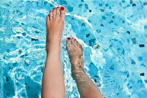 A pair of feet in a swimming pool with clear water.