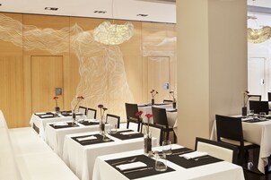 Espaço de refeições com mesas preparadas para o serviço, apresentando um design moderno com painéis de madeira e uma luminária única.