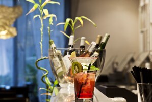 Um bar com um coquetel, um copo de água e uma garrafa de champanhe.