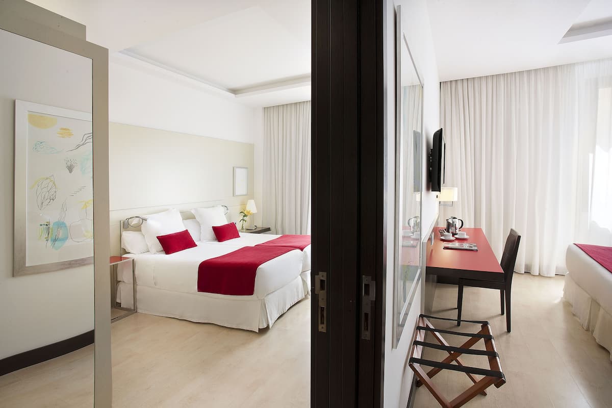 A hotel room with a bed, a desk, and a chair.