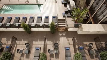 A rooftop pool area with sun loungers, a small pool, and a staircase leading to an upper deck.