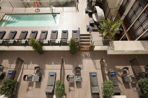 A rooftop pool area with sun loungers, a small pool, and a staircase leading to an upper deck.