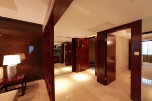 Un pasillo de hotel con puertas de madera, una lámpara y un espejo.