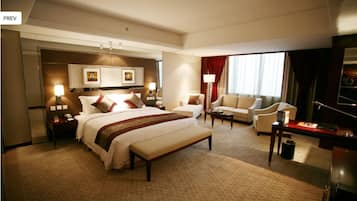 Amplia habitación de hotel con una cama grande, un sofá, un escritorio y un televisor.