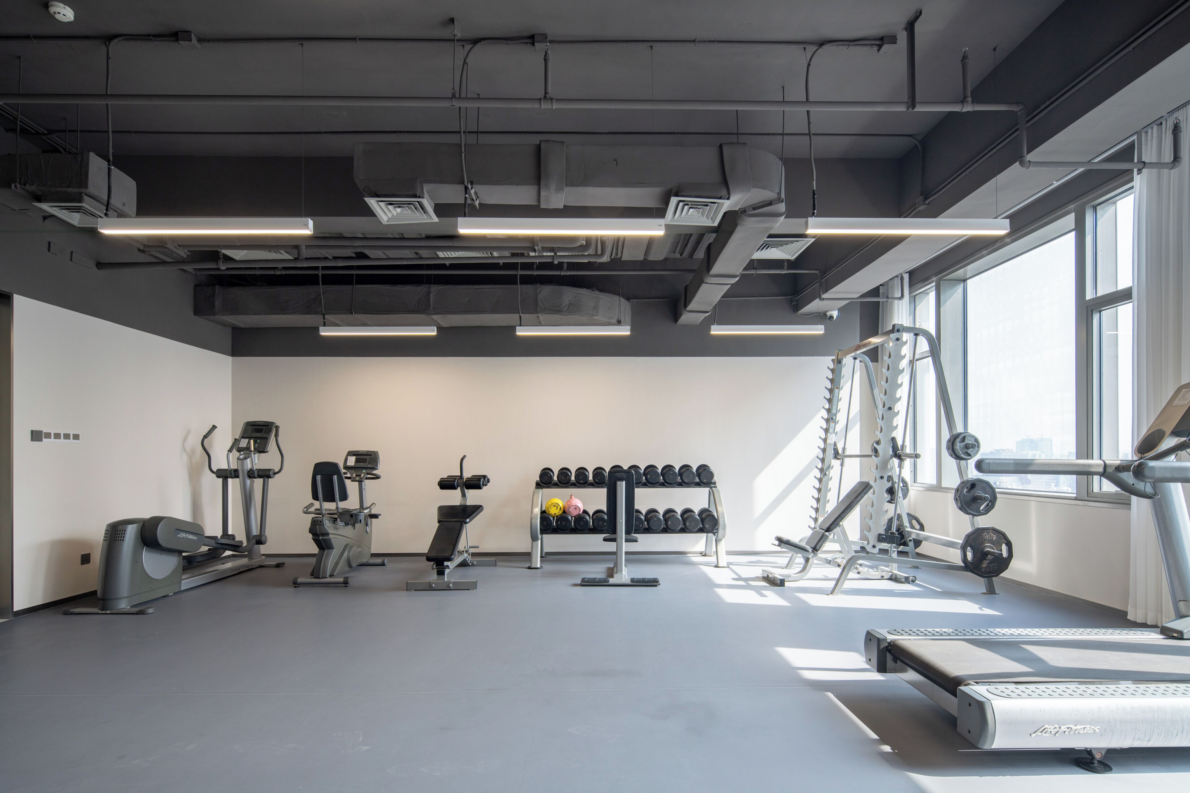 A gym with exercise equipment, a rack of dumbbells, and a treadmill.