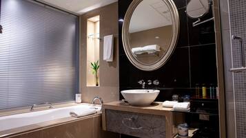A modern bathroom with a large oval mirror, a bathtub, a sink, and a shower area.