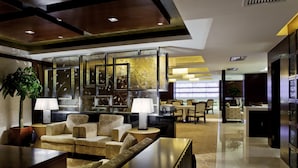 Una hall moderna con angolo relax, reception e un pannello decorativo in vetro.