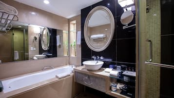 Une salle de bain moderne avec une baignoire, un grand miroir ovale, un lavabo et une douche à parois de verre.
