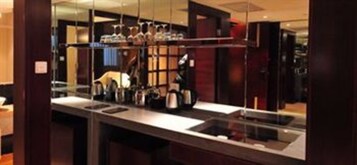 Una cocina moderna con una isla grande, electrodomésticos de acero inoxidable y un separador de vidrio.