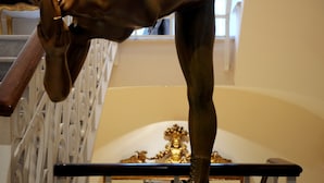 A bronze statue of a man in a dynamic pose on a platform. - Hotel Villa Duse (Rome)