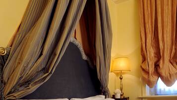 A bed with a canopy, white linens, and a book on it.