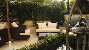 An outdoor seating area with a water feature, a large umbrella, and a decorative metal structure. - Hotel Villa Duse (Rome)