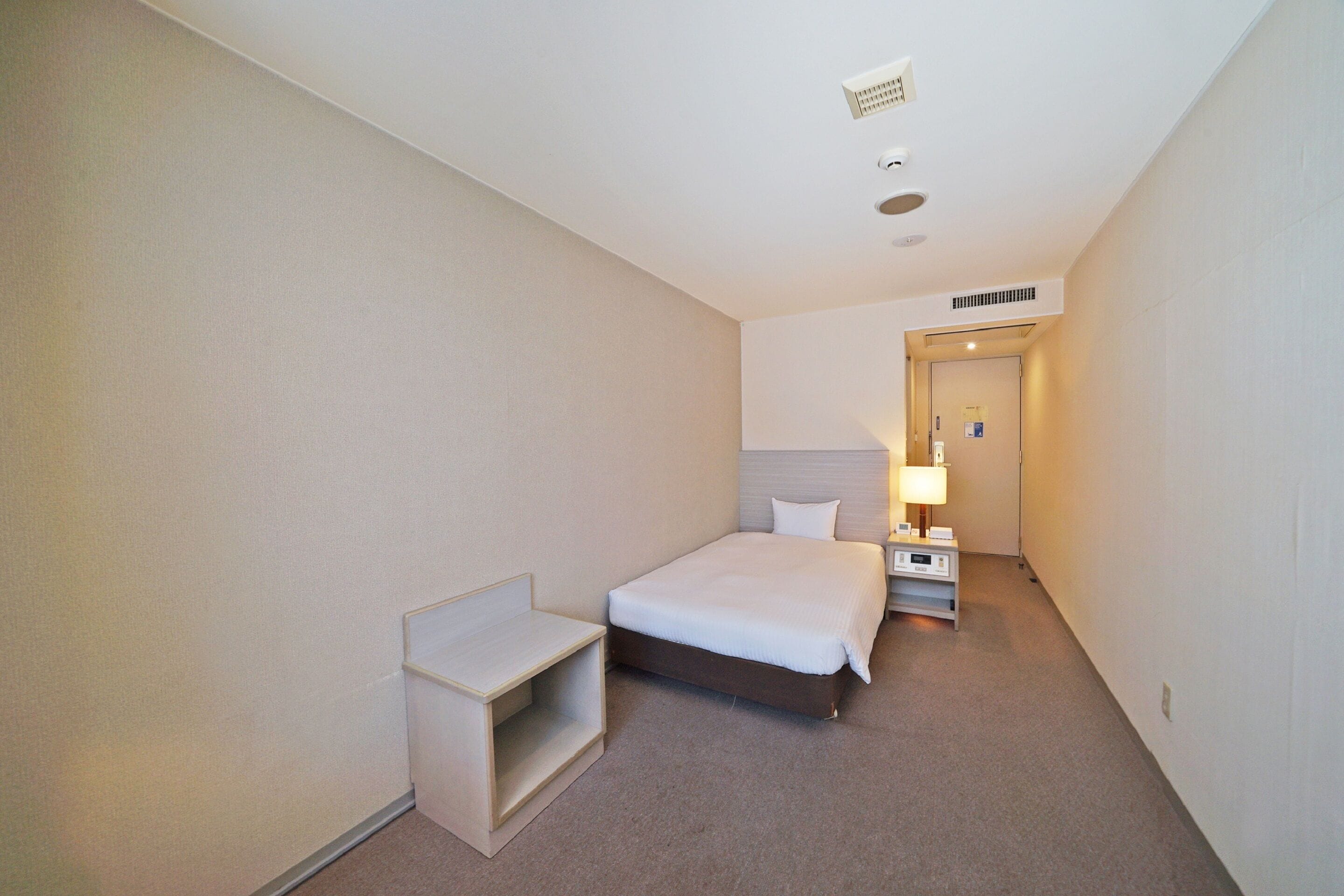 Ein Hotelzimmer mit Bett, Nachttisch und kleinem Schreibtisch.