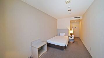 Ein Hotelzimmer mit Bett, Nachttisch und kleinem Schreibtisch.