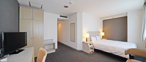 Une chambre d’hôtel comprenant un lit, un bureau avec une télévision, une chaise et une armoire.