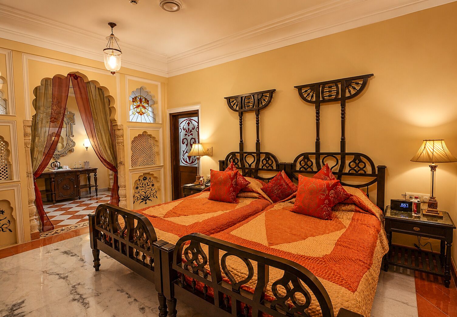 A traditional room with a bed, a nightstand, a lamp, and decorative elements.