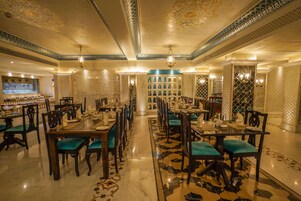 Un vaste espace dédié à la salle à manger, avec de nombreuses tables et chaises, des motifs décoratifs au plafond et un sol à motifs.