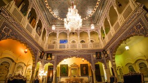 Un interior ornamentado con una araña, techos abovedados y muebles tradicionales.