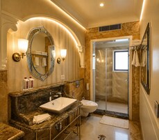 Um banheiro luxuoso com toucador de mármore, um espelho grande, chuveiro e porta de vidro para o box.