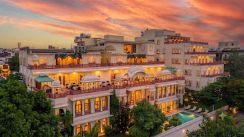 Un hotel de varios pisos con arquitectura tradicional, piscina y abundante vegetación.