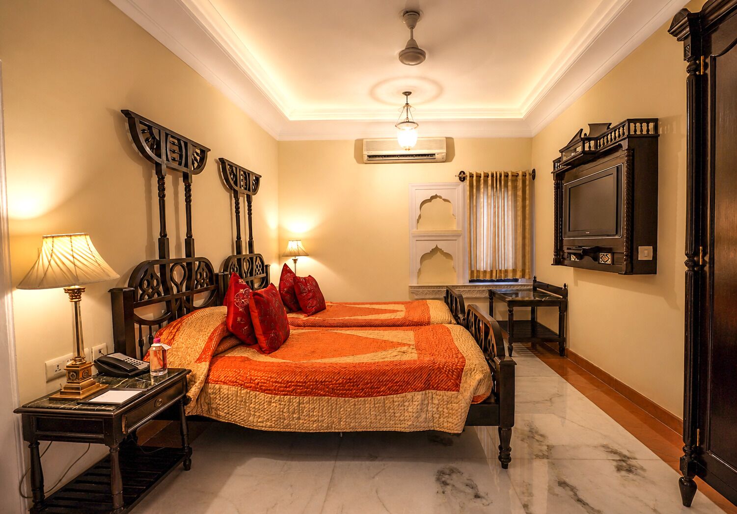 A hotel room with a bed, bedside tables, a desk, a television, and a ceiling fan.