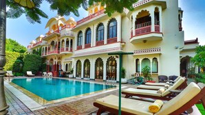 Un área de piscina con sillones de descanso y un edificio de arquitectura tradicional.