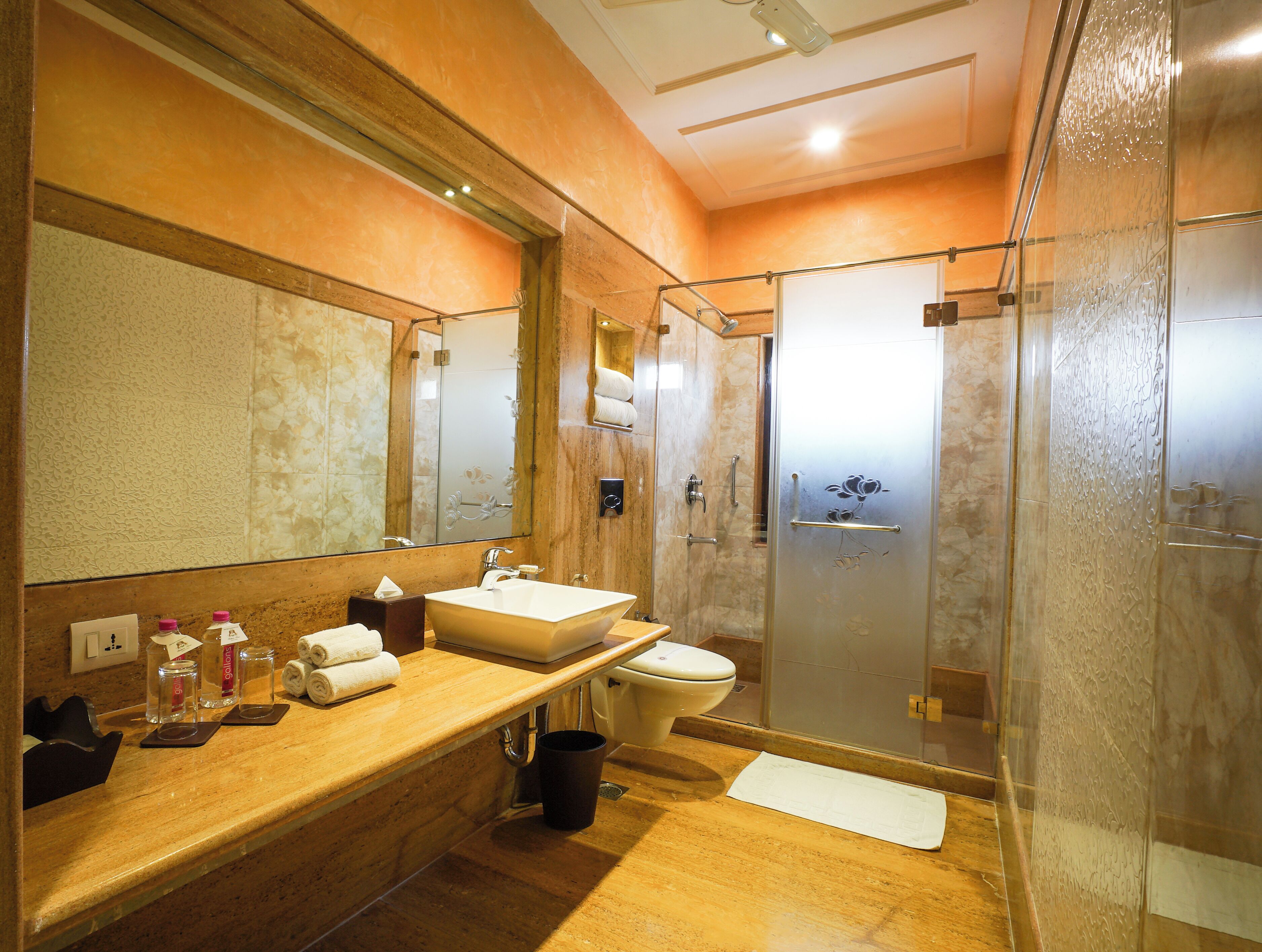 A bathroom with a large mirror, a sink, a toilet, and a shower enclosure.