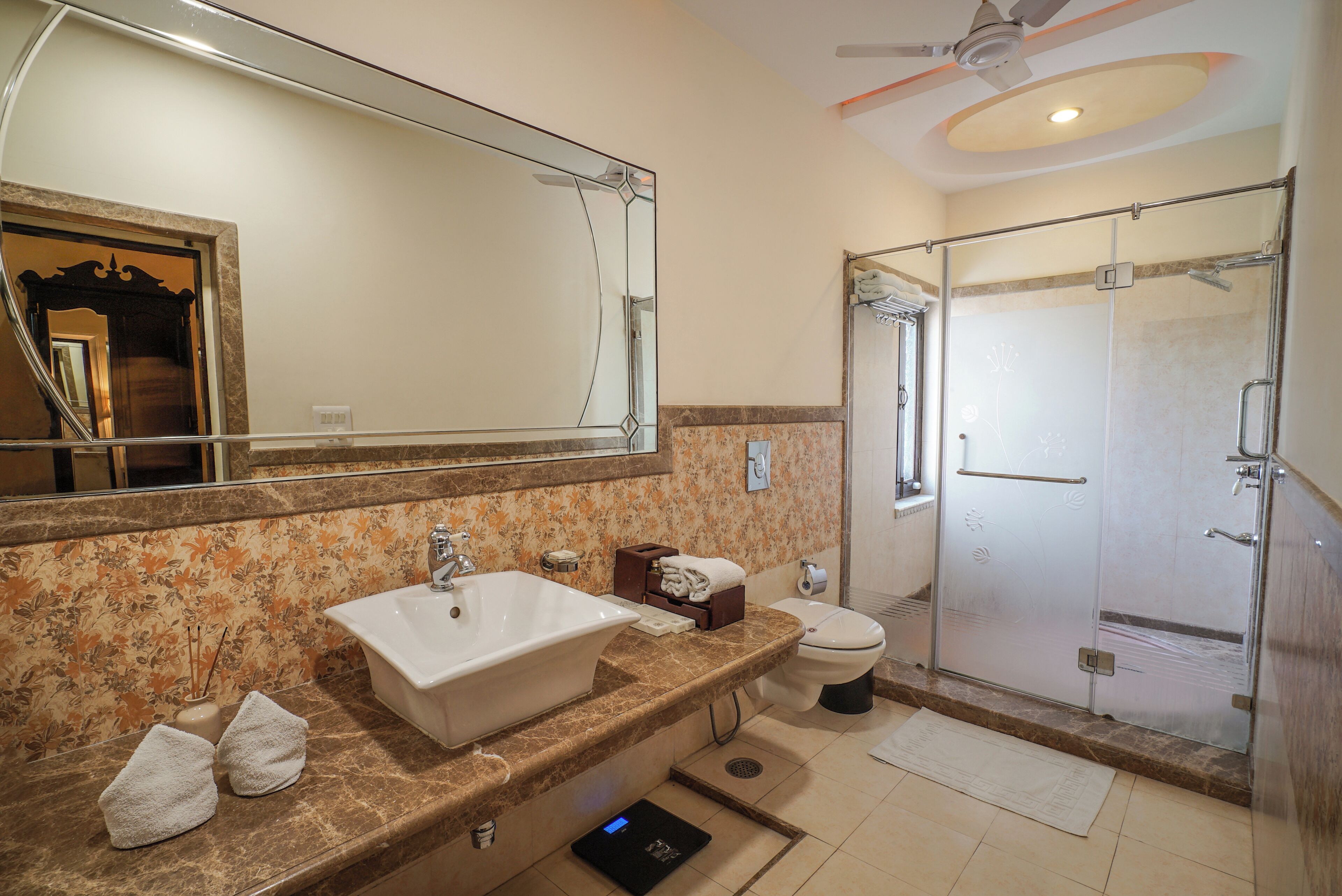 A bathroom with a large mirror, a sink, a toilet, and a shower area.