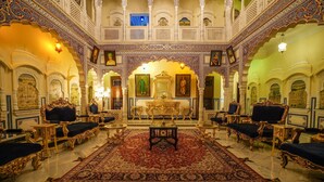Un salón imponente con arcos decorativos, una mesa central y un mobiliario lujoso.