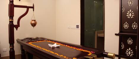 A room with a wooden massage table, a scale, and a decorative wall panel.
