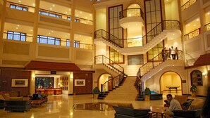 A spacious lobby with multiple seating areas, a grand staircase, and a reception desk. - Lagoona Resort (Mawal)