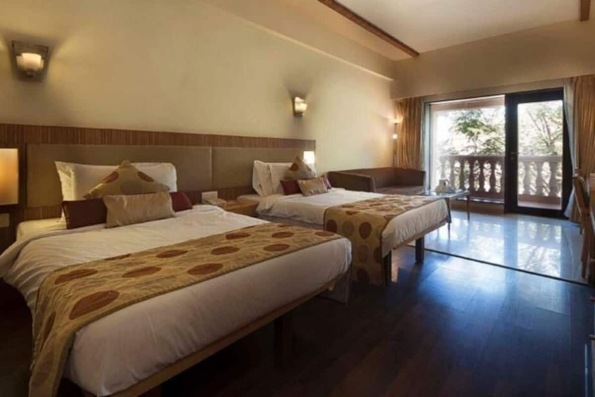 Hotellihuone, jossa on kaksi sänkyä, parveke ja puinen katto.