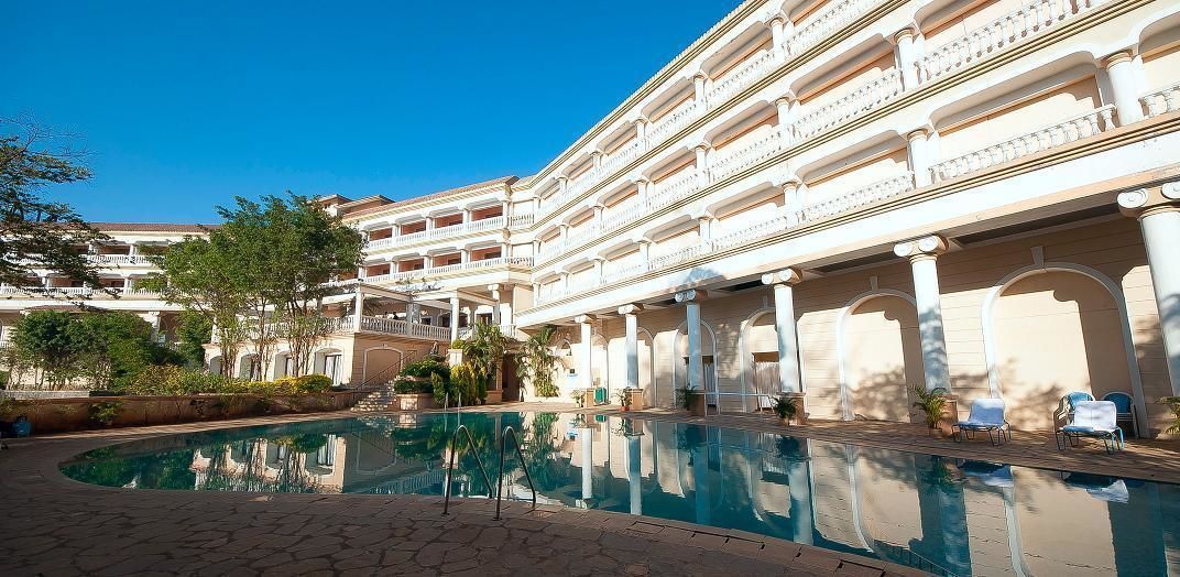 Un hôtel doté d’une grande piscine, de nombreux balcons et d’une cour intérieure arborée.