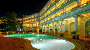 A multi-story hotel with a swimming pool, outdoor lighting, and a landscaped garden. - Lagoona Resort (Mawal)