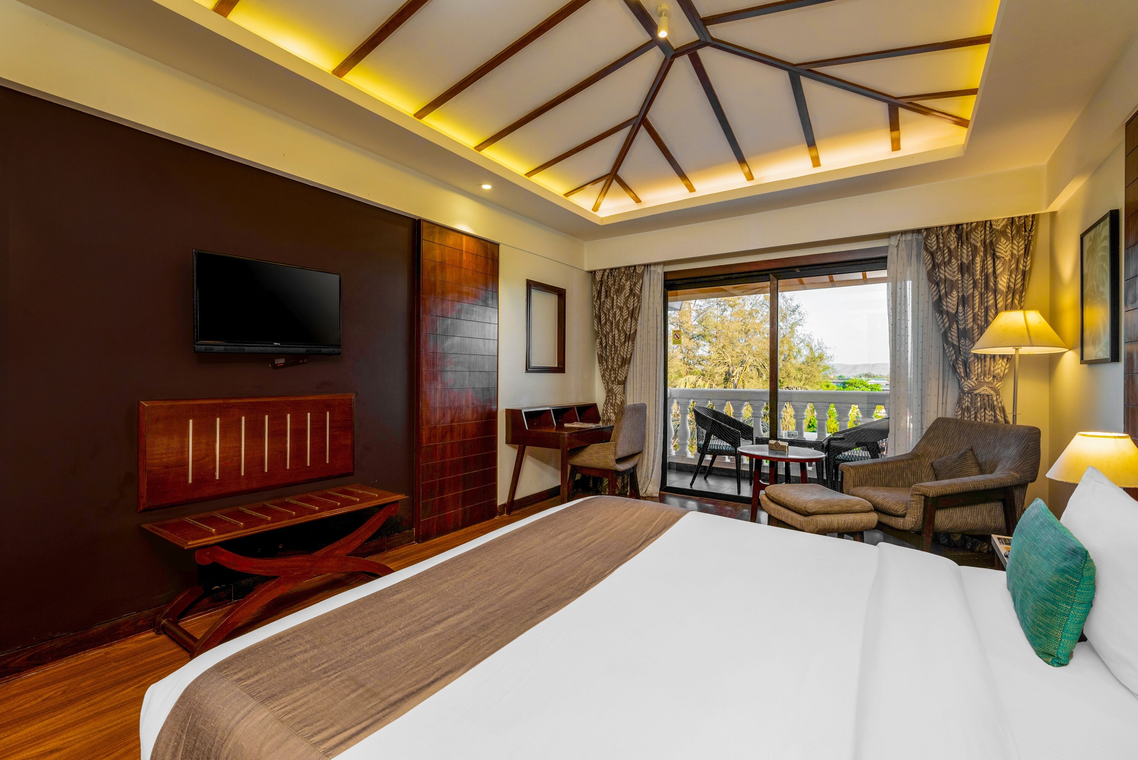 Une chambre d’hôtel dotée d’un grand lit, d’un bureau, d’une chaise, d’une télévision et d’un balcon aménagé avec du mobilier d’extérieur.