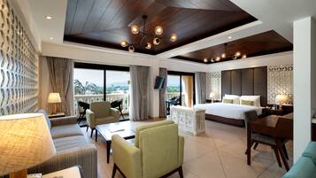 A hotel room with a large bed, a sitting area with a sofa and armchairs, a dining table, and a view of the city.