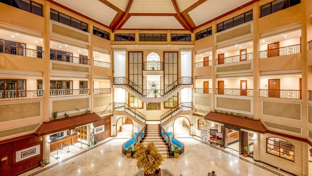 A multi-level hotel lobby with a central staircase, multiple balconies, and a reception area. - Lagoona Resort (Mawal)