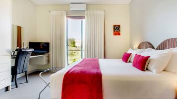 A hotel room with a bed, a desk, a chair, a television, and a window with curtains.