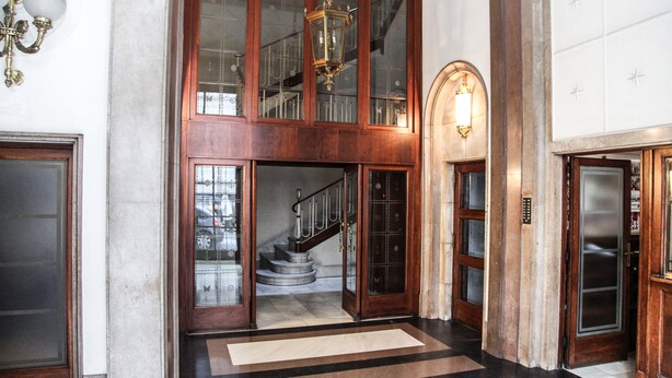 A grand lobby with a staircase, wooden doors, and a chandelier. - Petit Hotel (Barcelona)